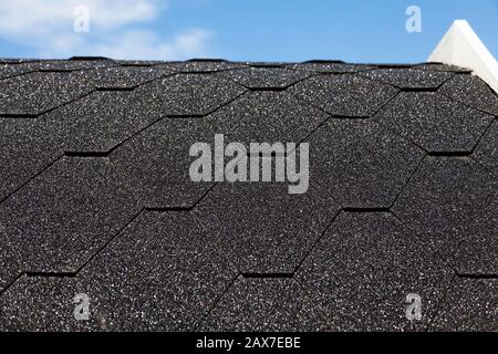 black roof with hexagonal parts with blue summer sky in the background Stock Photo