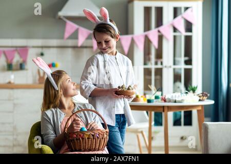 Smiling girl and boy make Easter basket at home in the kitchen Stock Photo