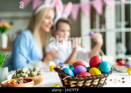 Closeup, colored eggs, on blurred background of mother and her cute son. Stock Photo