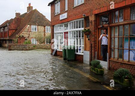 Bosham, West Sussex. 10th Feb 2020. UK Weather: A gallery worker photographs flooding as tides rise in the wake of Storm Ciara and flood the village of Bosham, West Sussex, Uk Monday February 10, 2020.  Many places in the UK remain with yellow weather warnings as the Storm Ciara weather front continues.  Photograph : Luke MacGregor Credit: Luke MacGregor/Alamy Live News