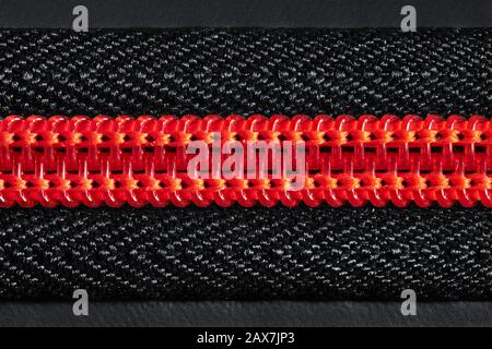 red zipper fastener on black, close-up Stock Photo