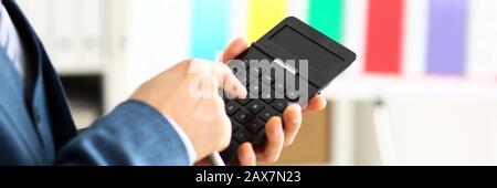 Male arm in suit hold calculator pressing buttons Stock Photo