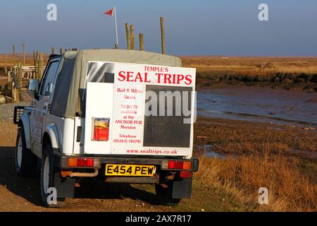 A 4-wheel drive vehicle parked by the quayside advertising seal trips to Blakeney Point at Morston, Norfolk, England, United Kingdom, Europe. Stock Photo