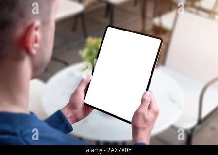 Tablet mockup in man hands in coffee shop. View over guy shoulder Stock Photo