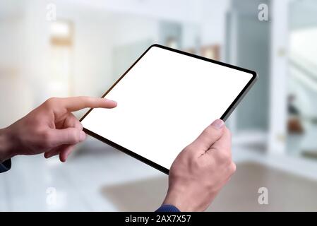 Tablet mockup in man hands. Living room interior in background Stock Photo