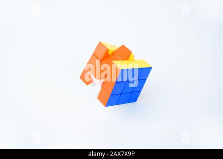 A solved rubik's cube placed on a white background displaying bright blue orange and yellow color Stock Photo