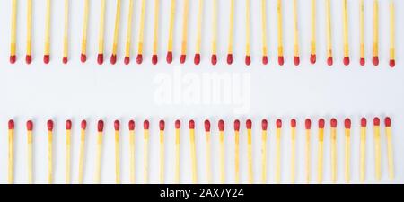 Two row's of red wooden match stick's facing each other arranged on a white background Stock Photo