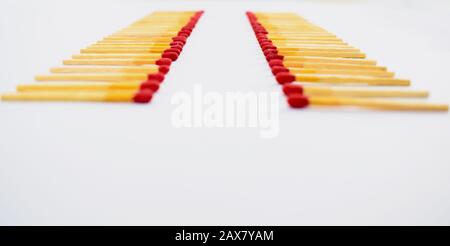Wooden red match sticks arranged in two similar row while facing each other on a white background Stock Photo