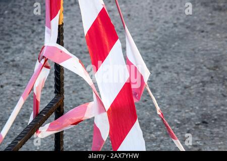 Signal red and white tape hanging on a metal fence, danger Stock Photo