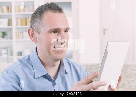 Smiling Deaf man talking using sign language on the tablets's cam Stock Photo