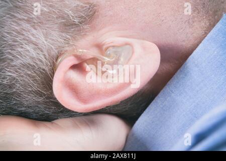 close-up on the hearing aid in the man's ear Stock Photo