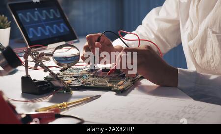 View of woman's hands testing electronic board in laboratory using multimeter tester and other technologies Stock Photo