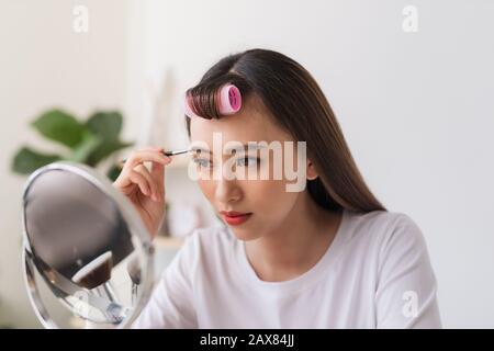 Attractive talented female blogger reviews beauty product for video blog, gives advice to girls and women, films process on camera. Stock Photo