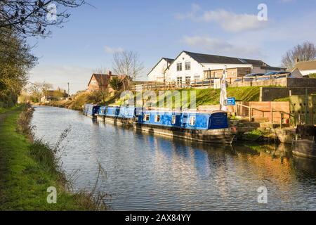 A calm sunny landscape in eaarly January showing the Kennet and Avon canal and narrow boats moored at Honeystreet in the Vale of Pewsey in Wiltshire E Stock Photo