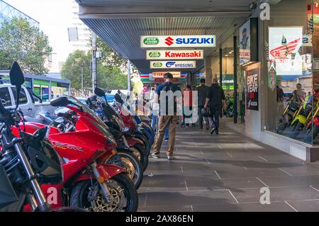 Melbourne, Australia - April 4, 2017: People walking street past scooters and motorcycles display Stock Photo