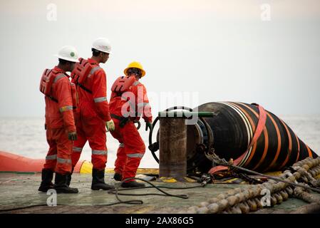 marine crew working on deck  during hose handling operation carried out at sea
