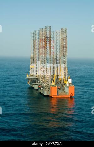 Aerial view of a transporter ship carrying 3 drilling platforms to Sharjah Port for re-fitting. Stock Photo