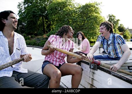 Friends rowing together in the park. Stock Photo