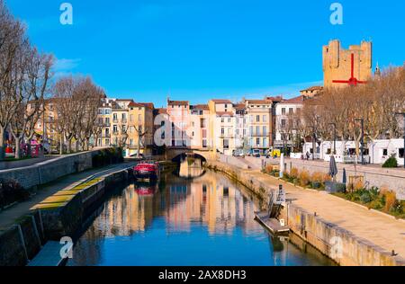 NARBONNE, FRANCE - DECEMBER 27, 2016: The Canal de la Robine channel passing through Narbonne, France, with the Pont des Marchands bridge in the backg Stock Photo