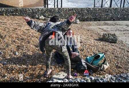 Wacky couple on Brighton beach appearing to be high or drunk UK Stock Photo