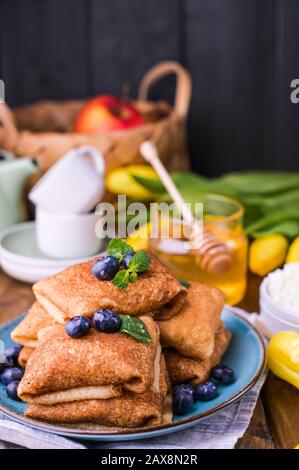 Thin pancakes with cottage cheese and strawberries. Healthy traditional breakfast concept. Baking for a traditional Russian carnival in the spring, Maslenitsa. Copy space. Stock Photo