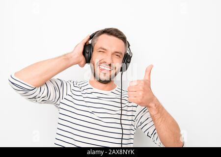 Portrait of happy man in headphones listening music and showing thumb up Stock Photo