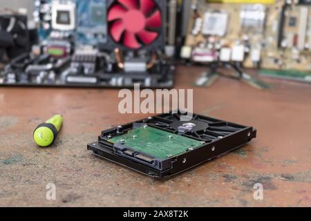 A broken and dusty computer hard drive lies on a table in a repair shop Stock Photo