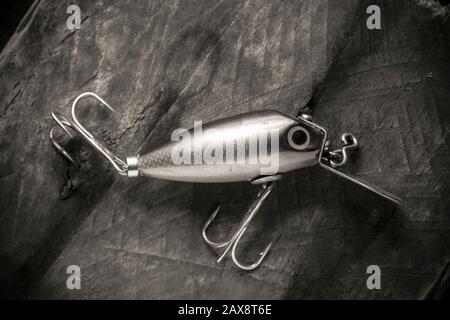 An old wooden fishing lure equipped with three treble hooks for