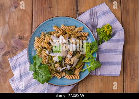 Cime di rapa pasta in a plate on with parmesan on a wooden table. Traditional food of the south of Italy, from Puglia. Rustic style photo.  Stock Photo