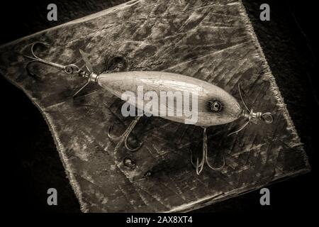 An old, wooden South Bend lure equipped with three treble hooks  photographed on a dark, slate background. These lures were designed to  float on the su Stock Photo - Alamy
