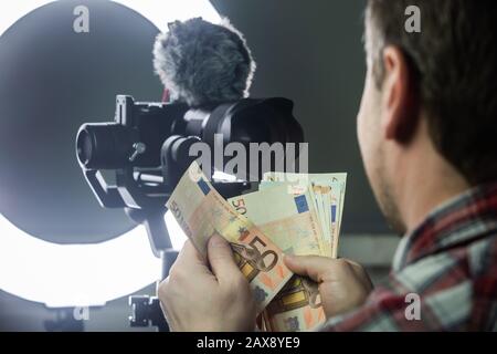 Male vlogger counting money from vlogging Stock Photo