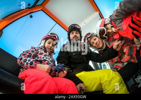 Family riding cabin cable car on winter vacation skiing. Family on winter vacations ski trip taking selfie inside of cabin with amazing mountain view Stock Photo