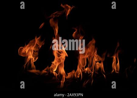 On fire flames at the black background, Burning red hot sparks rise, Fiery orange glowing flying particles Stock Photo