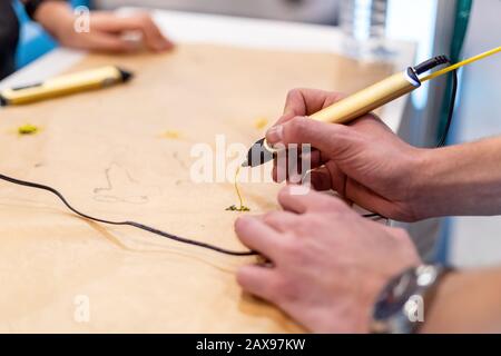 Person creating with 3D handle pen. Teenager using modern printing pen. Creative craft class Stock Photo