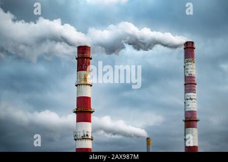 Dark toxic smoke clouds coming out of factory chimney. Air pollution and global warming caused by old industrial power plant Stock Photo