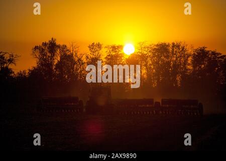 Agricultural mechanical seeders of grain crops. Tactor with a seeder sows grain in the field. A farmer on a tractor with a seeder processes the field. Stock Photo