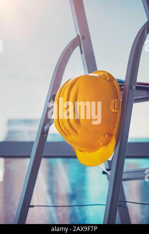 Construction site, closeup photo of a yellow helmet on the stairs, renovation in the apartment, overhaul in the office, builders workplace Stock Photo