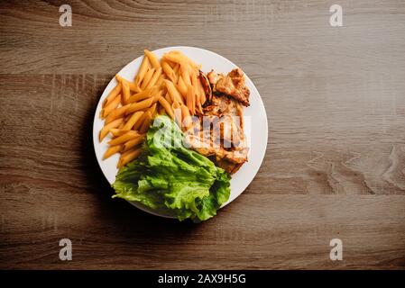 Top view on plate with chicken and green salad on the table Stock Photo
