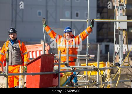 London, UK. 11th February, 2020.  A HS2 construction worker at London Euston station raises their arms moments after the UK government approved controversial High Speed 2 rail project, between London and Birmingham. HS2 due to be completed in 2040 is currently over budget and behind schedule, with warnings cost could rise to £106bn. Credit: Thamesfleet/Alamy Live News Stock Photo