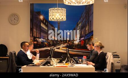 Office workers sharing a desk, London, England, UK. Stock Photo