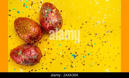 Premium gold Set of 3 golden red easter eggs painted with innovative acrylic on yellow background Ester concept. Top view Stock Photo