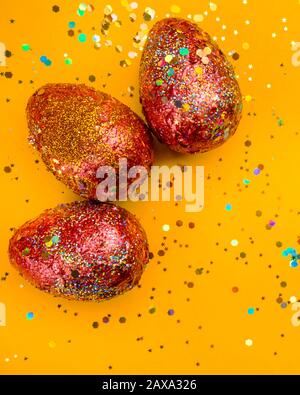 Premium gold Set of 3 golden red easter eggs painted with innovative acrylic on orange background Ester concept. Top view Stock Photo