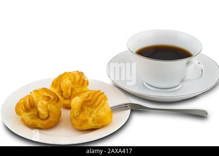 Eclairs in a white ceramic plate with metal folk and a cup of black coffee on white background with clipping path Stock Photo