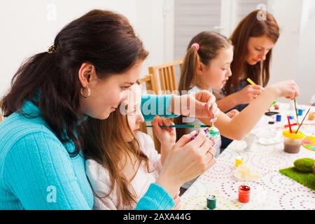 Mother and children painting colorful eggs. Family celebration Stock Photo