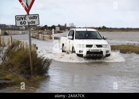 A vehicle travels on The Strood causeway, which joins the mainland to Mersea Island in Essex, to clear as, elsewhere in the UK, rain and wind caused by storm Ciara gave way to hazardous amounts of snow and ice. Stock Photo