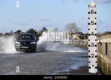 A vehicle travels on The Strood causeway, which joins the mainland to Mersea Island in Essex, to clear as, elsewhere in the UK, rain and wind caused by storm Ciara gave way to hazardous amounts of snow and ice. Stock Photo