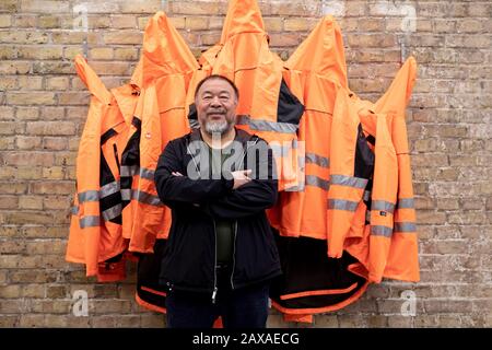 Berlin, Germany. 11th Feb, 2020. Ai Weiwei, Chinese artist, is standing in the studio in front of his artwork 'Safety Jackets Zipped the Other Way' in the 'version wall'. The various constructions of safety jackets, hooks and iron bars can be purchased as individual parts from the sponsor Hornbach and assembled by interested parties themselves. Credit: Christoph Soeder/dpa/Alamy Live News Stock Photo