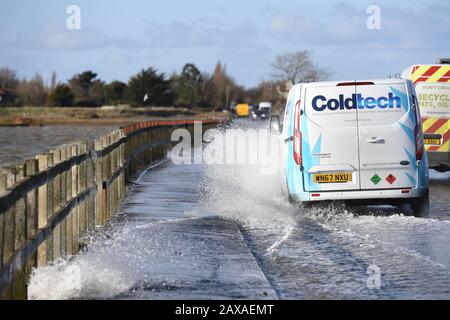 A vehicle travels on The Strood causeway, which joins the mainland to Mersea Island in Essex, to clear as, elsewhere in the UK, rain and wind caused by storm Ciara gave way to hazardous amounts of snow and ice. Stock Photo