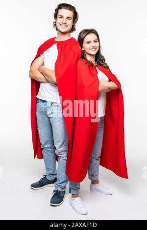 Super couple in masks and cloaks standing with hands on waist and looking at camera on white background Stock Photo