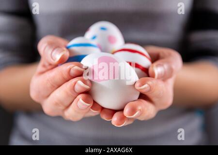 Female hands with Easter colorful eggs. Girl holding group of painting eggs in hands indoor. Easter holiday concept. Close up, selective focus Stock Photo